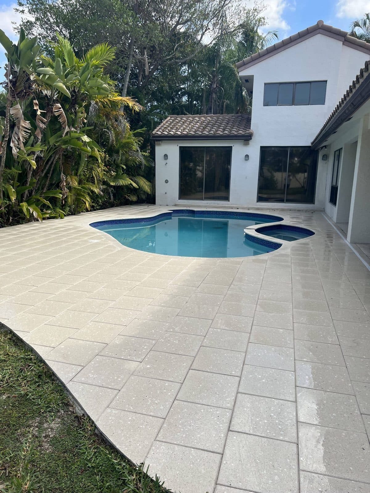 Clean light-tone pool-deck pavers around a screened pool
